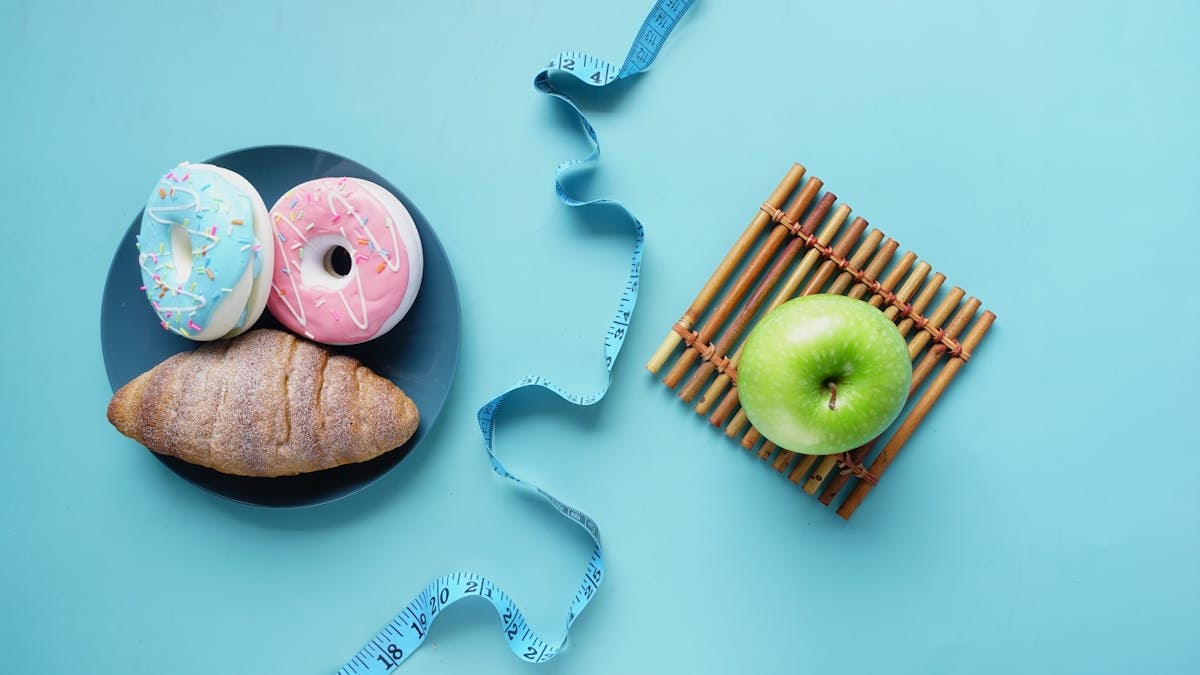 Contrast of healthy and indulgent foods with a measuring tape for weight management.